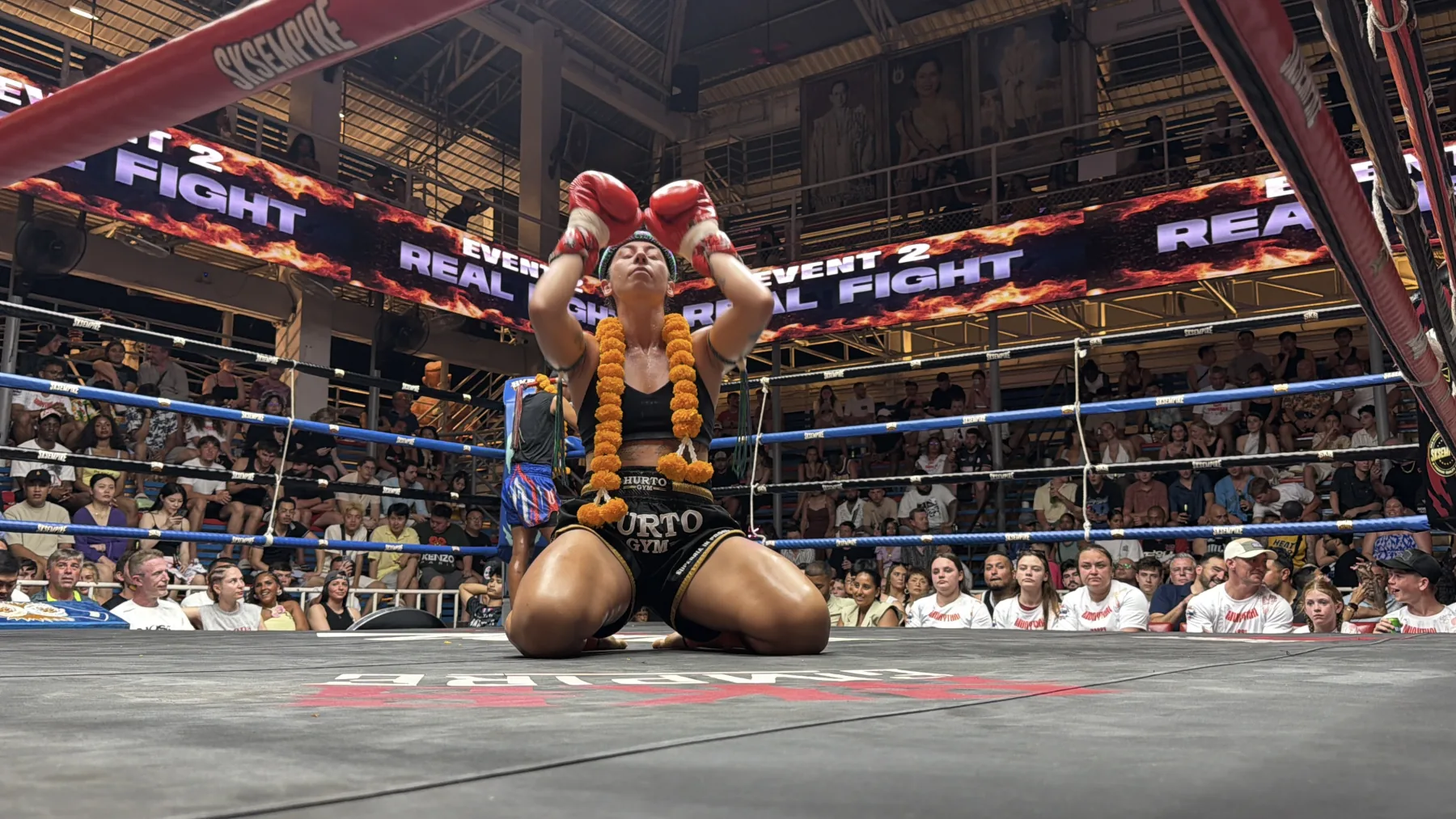 Jules Vassalos kneeling in a Muay Thai ring after a fight